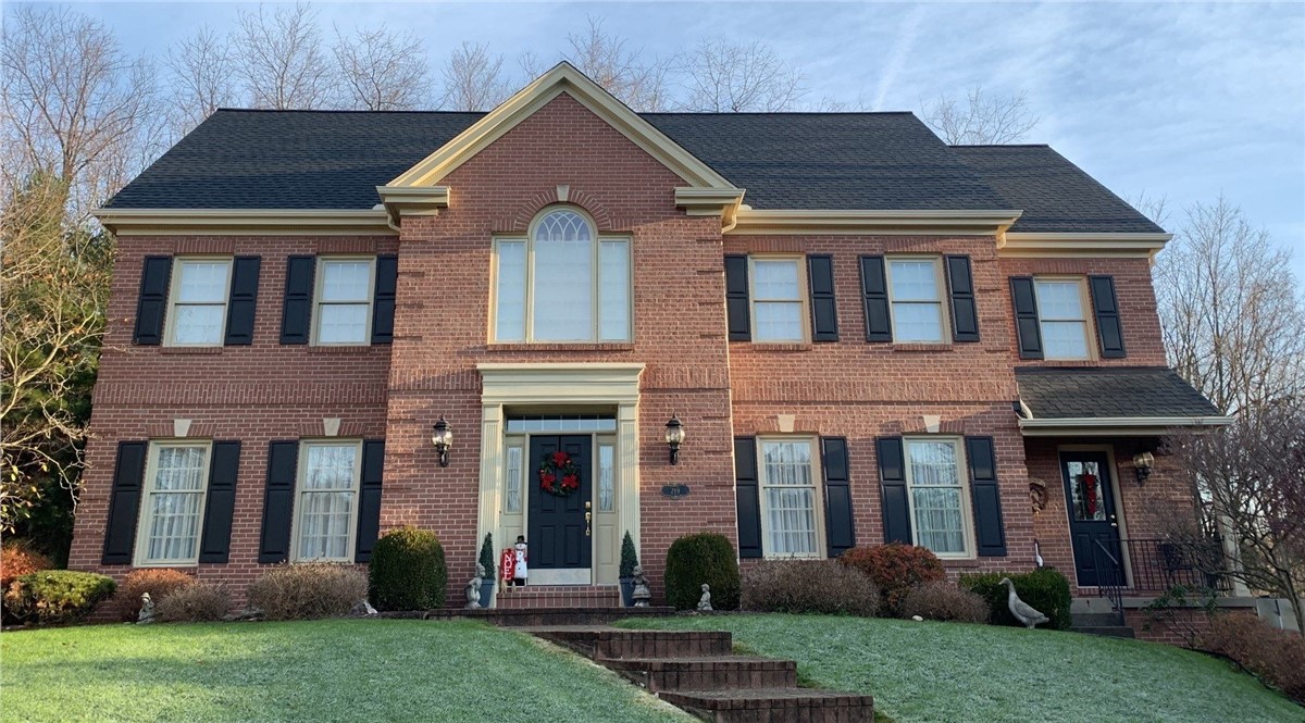 Brick colonial home with a completed Resnick roofing and siding project